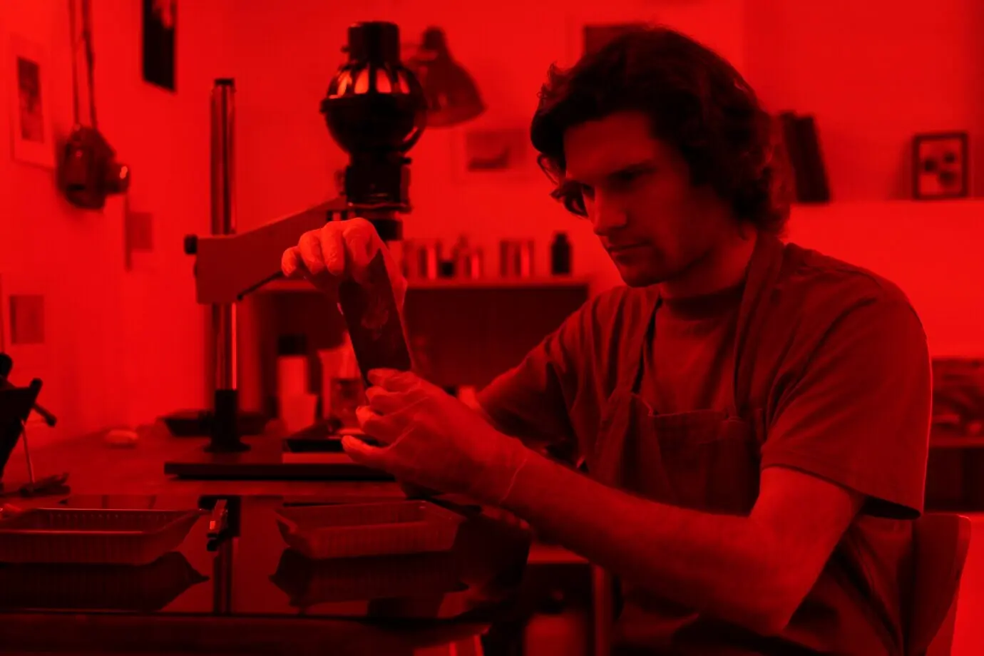 Мужчина работает в темной комнате, вид сбоку.